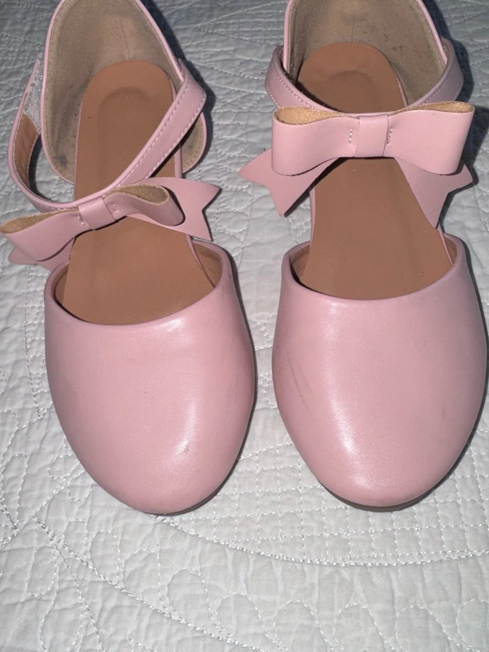 These pastel pink Mary Janes feature a delicate crisscross ankle strap adorned w